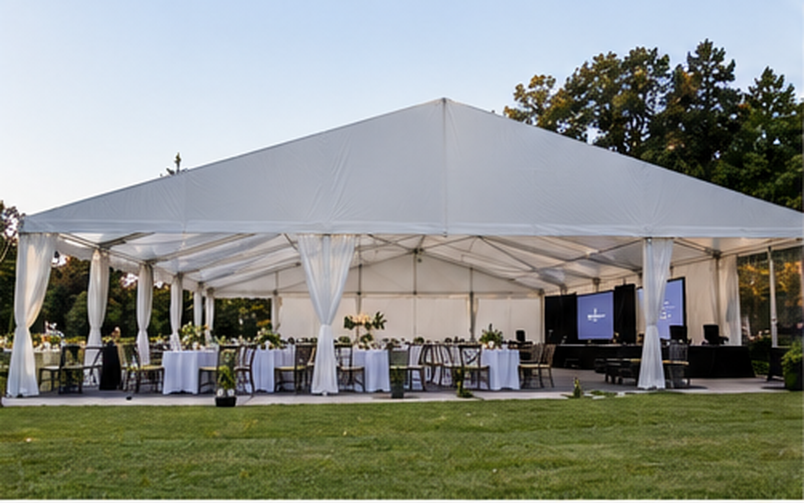 Frame tent arranged for an organized event with dining tables and a presentation screen.